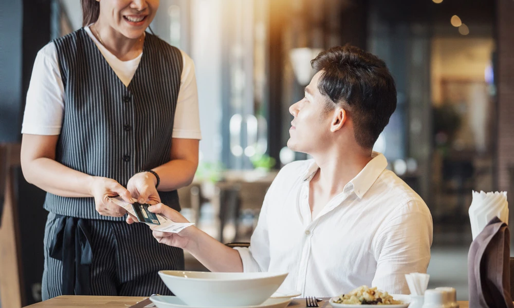 Une serveuse présentant la facture à un client