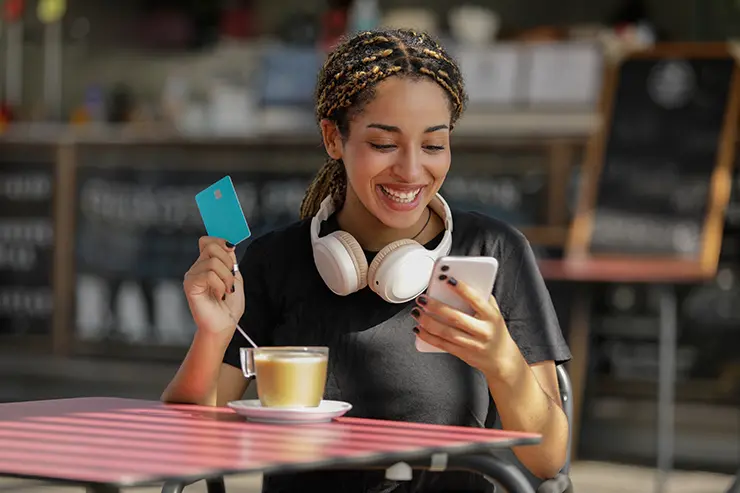 Femme tenant une carte de crédit et un téléphone